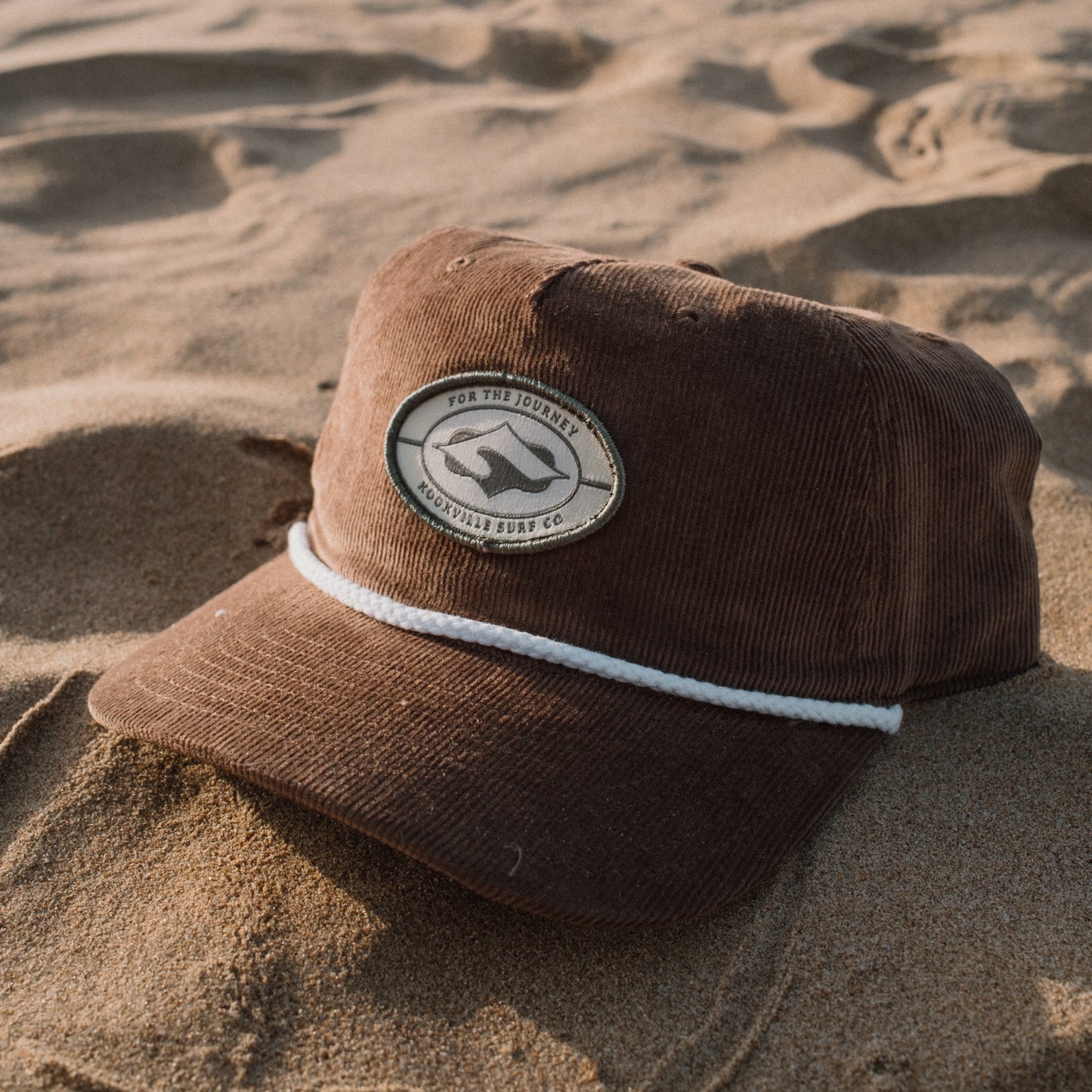 Brown cap with a logo on a sandy surface