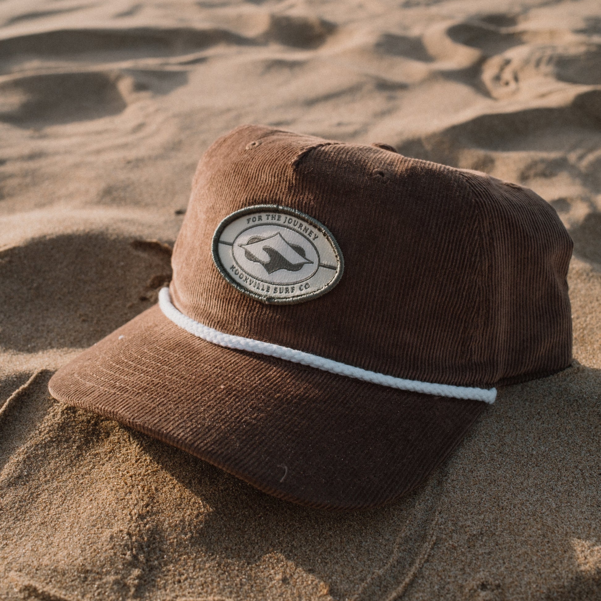 Brown cap with a logo on a sandy surface