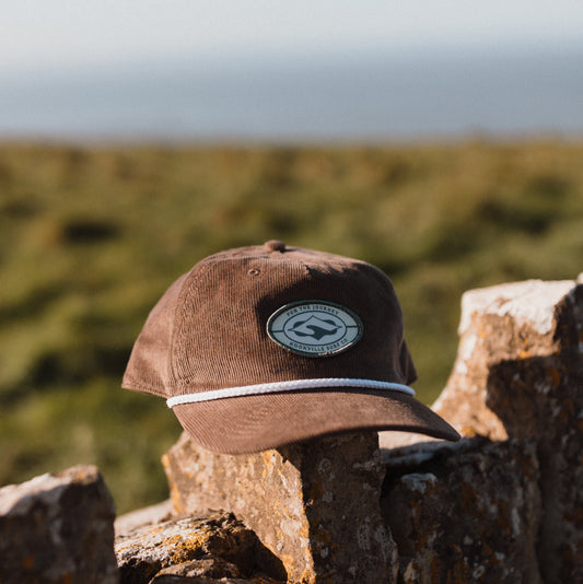 Brown cap with a logo on a wooden surface with a blurred natural background