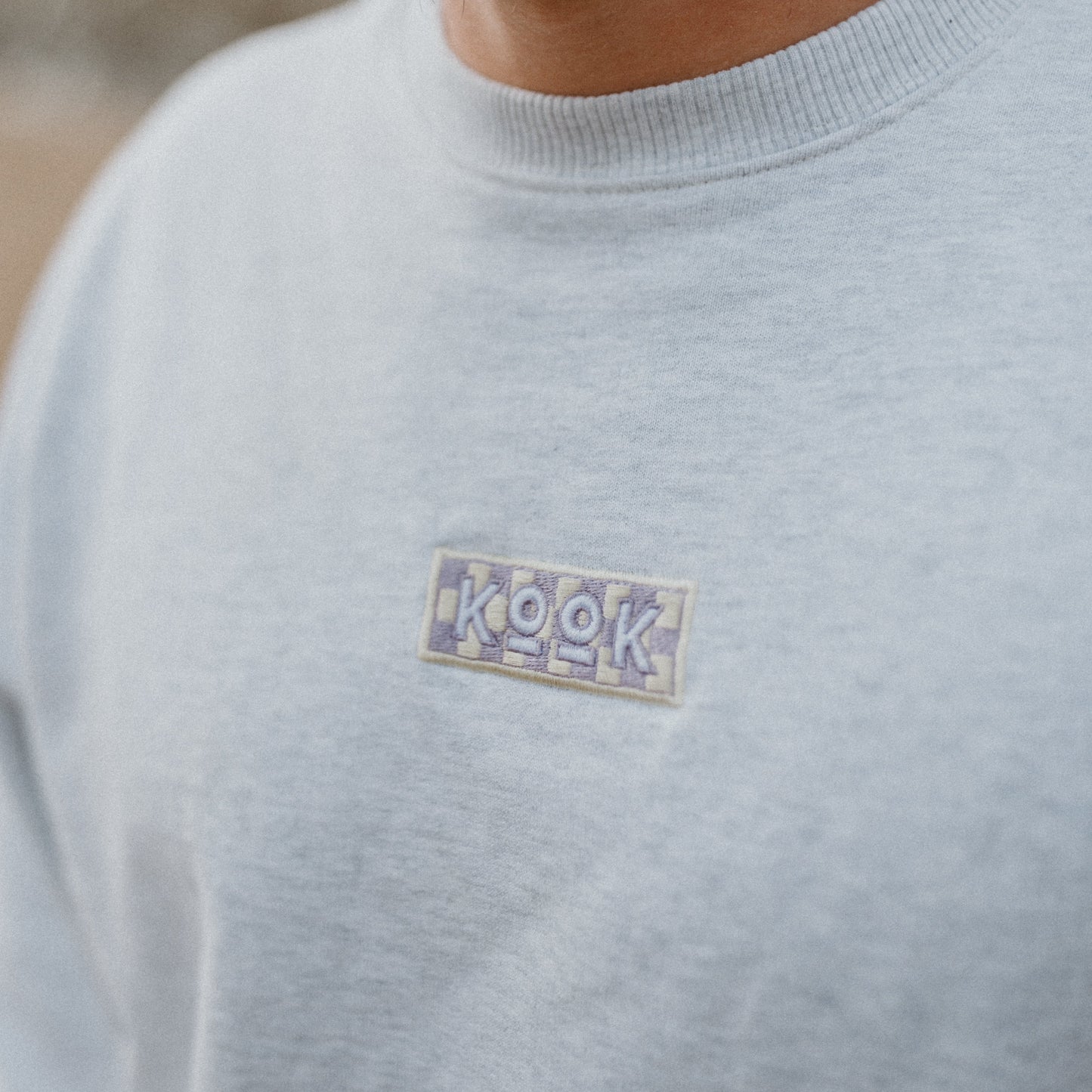 Man wearing a light gray sweater with a small logo on the chest.