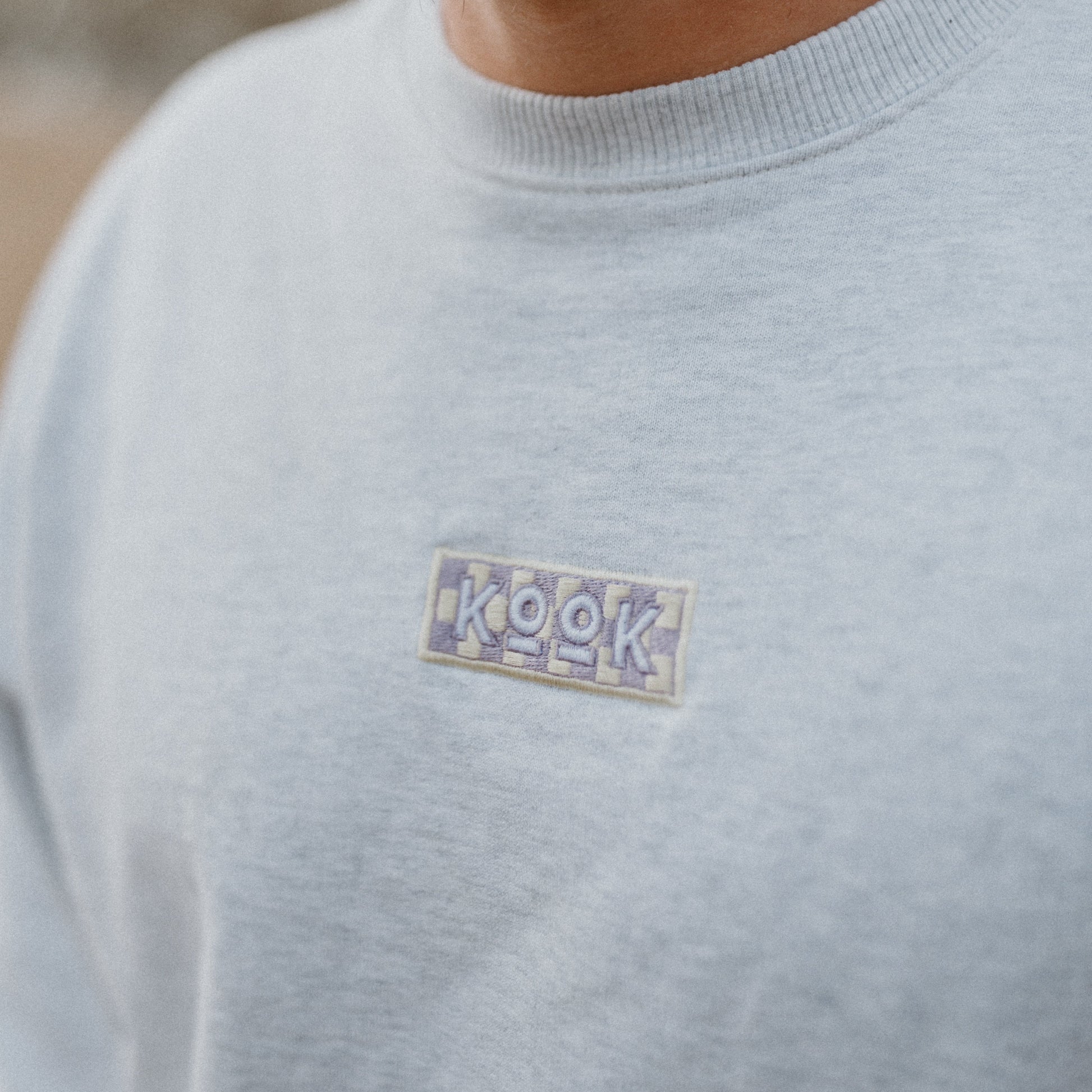 Man wearing a light gray sweater with a small logo on the chest.