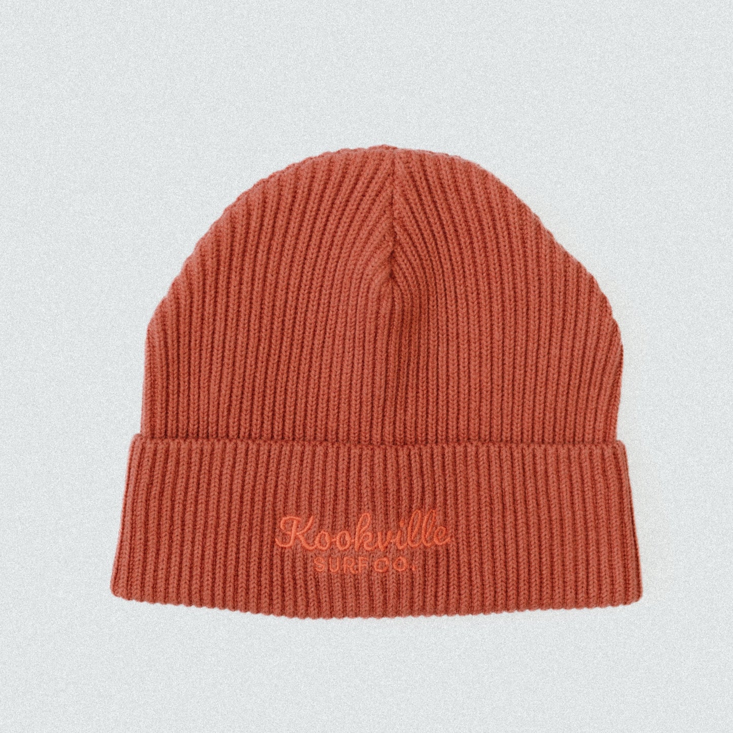 Orange knit beanie with 'Kookville' embroidery on a light gray background